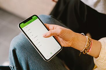 Eine Person hält ein Smartphone in der Hand, auf dem die HTW-Campus-App geöffnet ist.