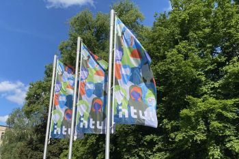 Fahnen am Campus Treskowallee. Das bunte, grafisch Motiv zeigt unterschiedliche Menschen. © HTW Berlin/Anja Schuster Fahnen am Campus Treskowallee. Das bunte, grafische Motiv zeigt unterschiedliche Menschen.